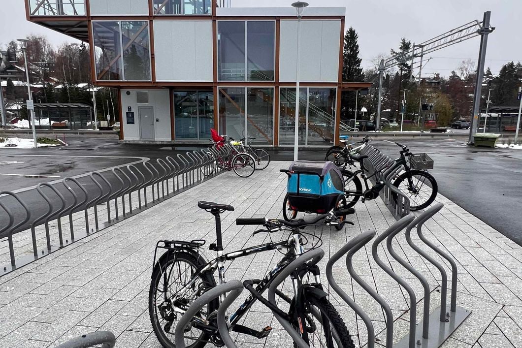 sykkel og sykkelvogn parkert ved togstasjon. Trappetårn i bakgrunnen.