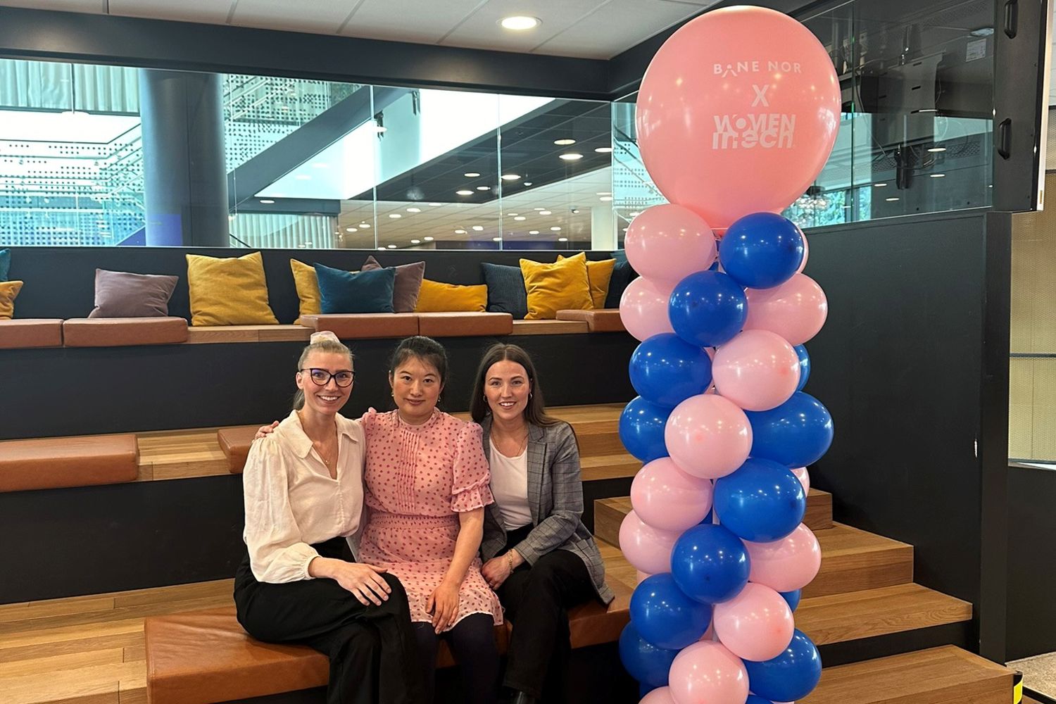 De tre som har opprettet kvinnenettverket sitter i ett rosa og blått pyntet lokalet.