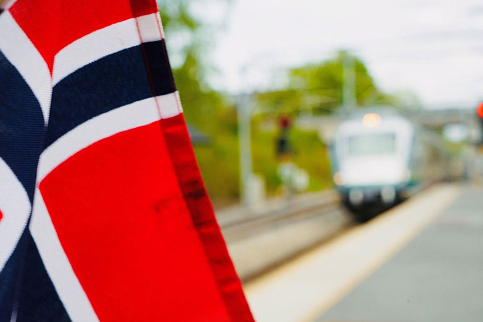 Bilde av et norsk flagg, med tog i bakgrunnen.