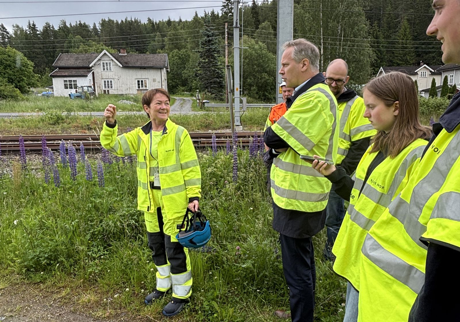 Menn og kvinner i arbeidstøy ved jernbanespor