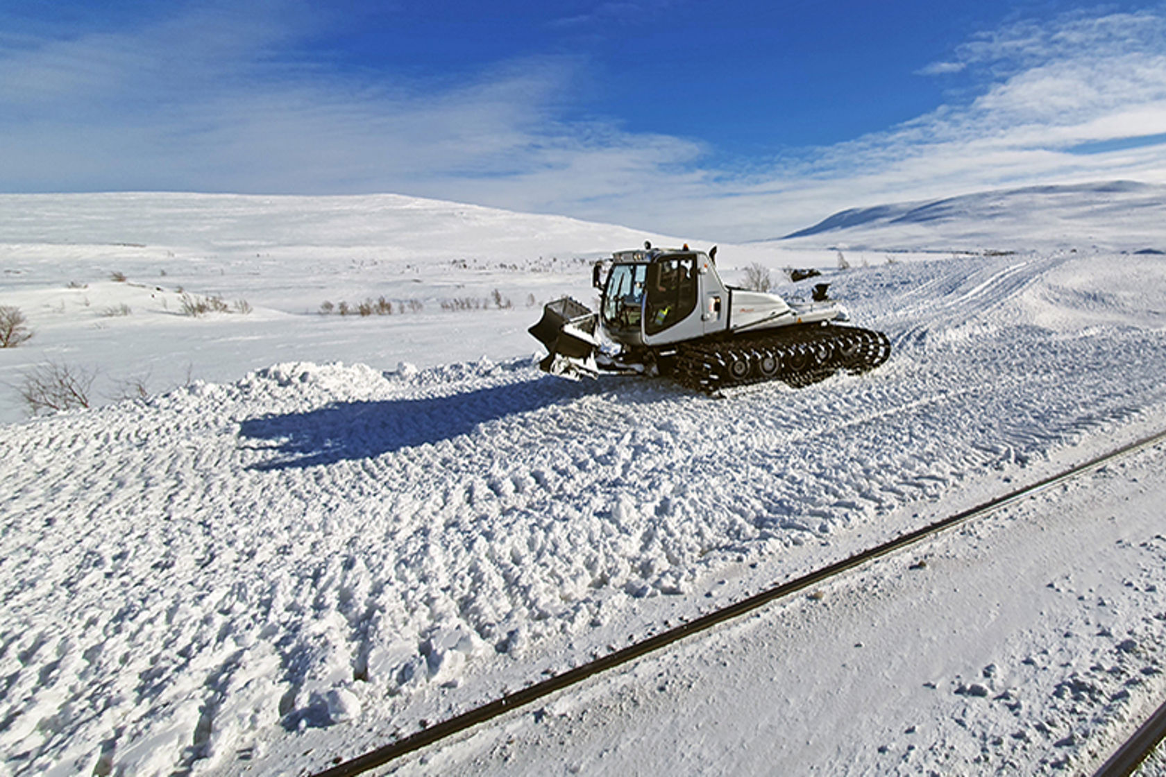 Bilde av en tråkkemaskin ved et jernbanespor på Saltfjellet.