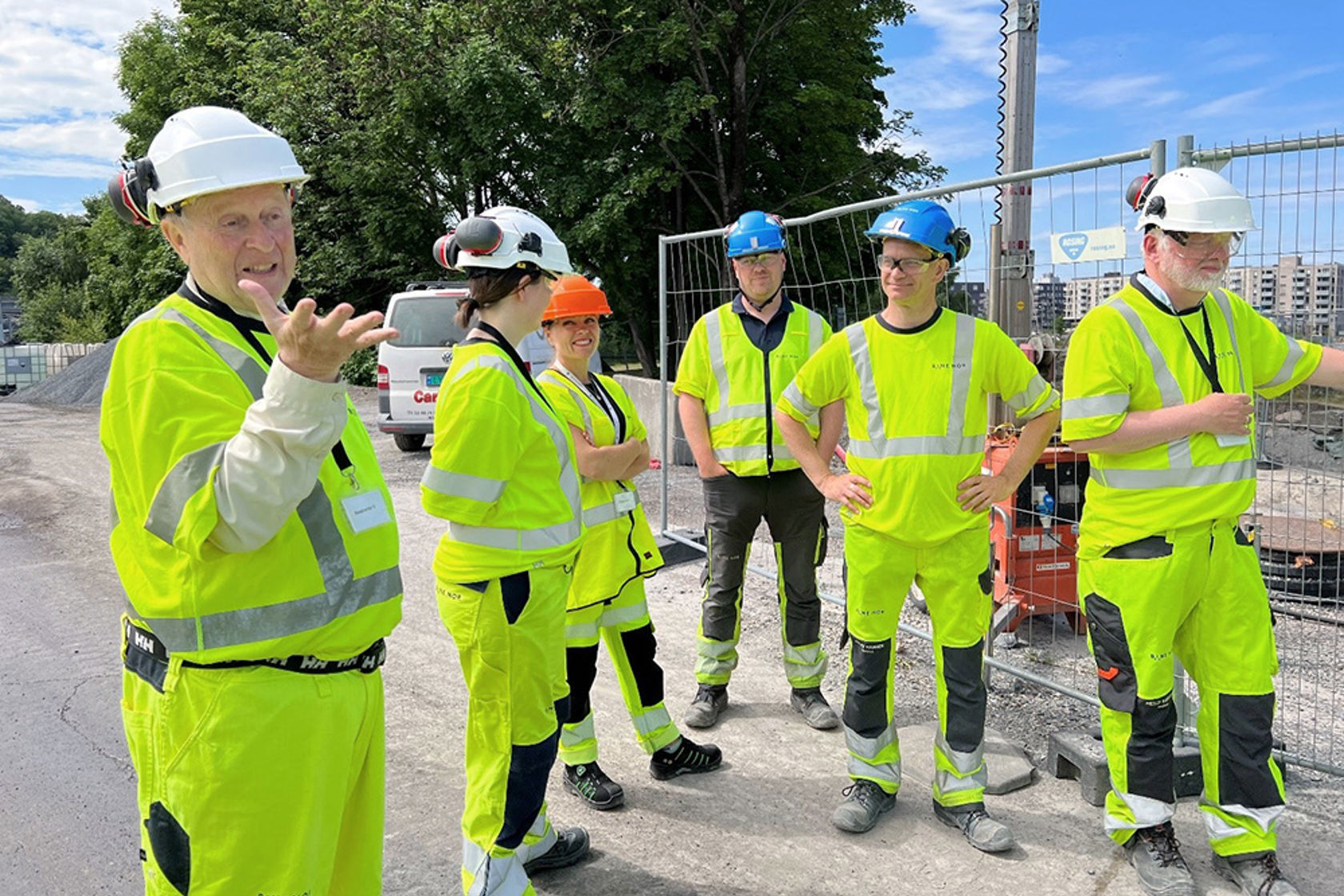 Personene er iført hjelm og anleggsklær, anleggsområdet i parken er i bakgrunnen.