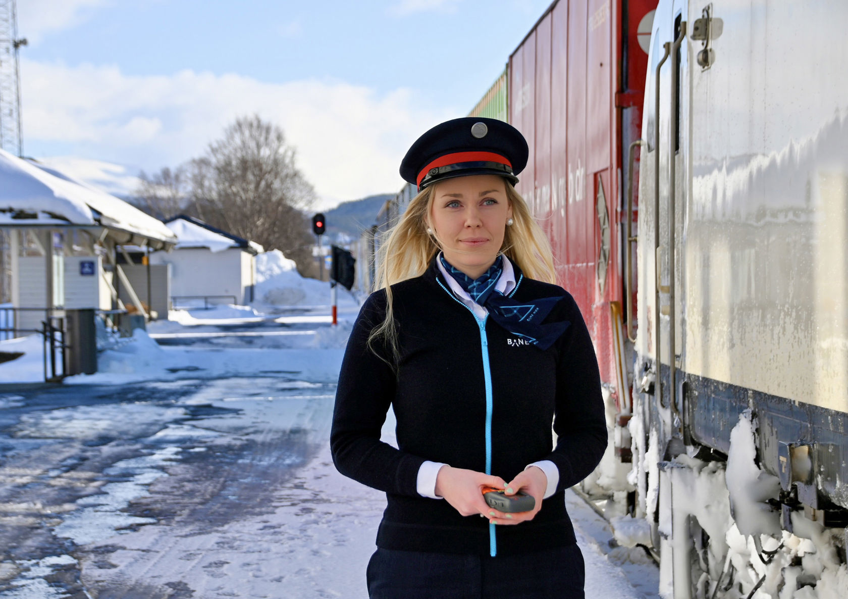 Bilde av ei kvinne i trafikkstyraruniform ved eit tog.