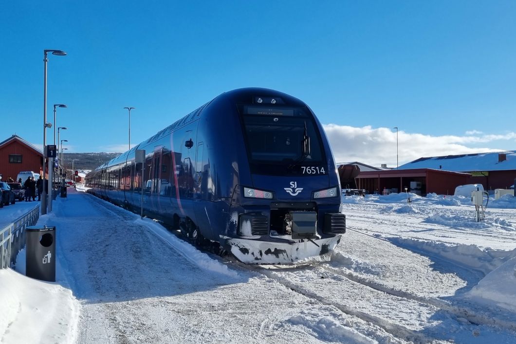 Tog står på Røros stasjon. Det er vinter, snø og klart vær.