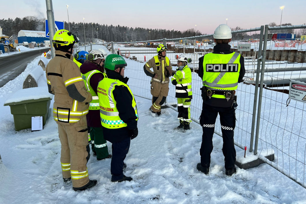 Menn i uniform og anleggstøy avbildet utendørs