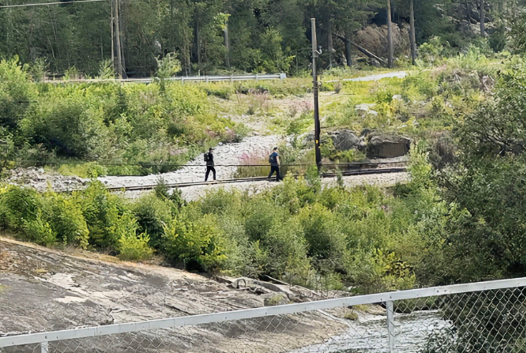 To menn går i jernbanesporet - bildet er tatt på avstand.