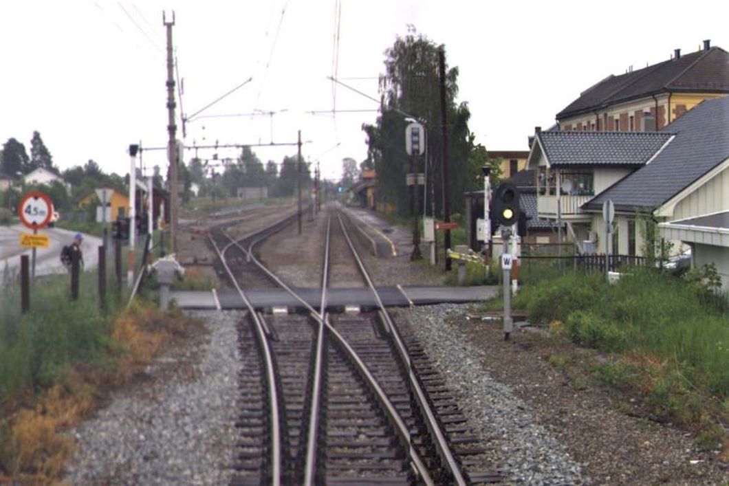 Bilde av en planovergang der jernbanen og en vei krysses.