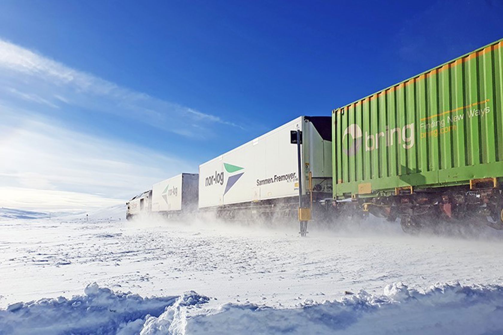 Et godstog kjører over et snødekt fjell