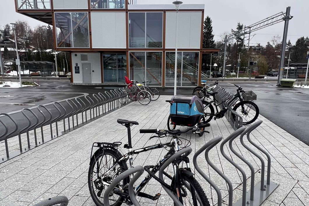 sykkel og sykkelvogn parkert ved togstasjon. Trappetårn i bakgrunnen.