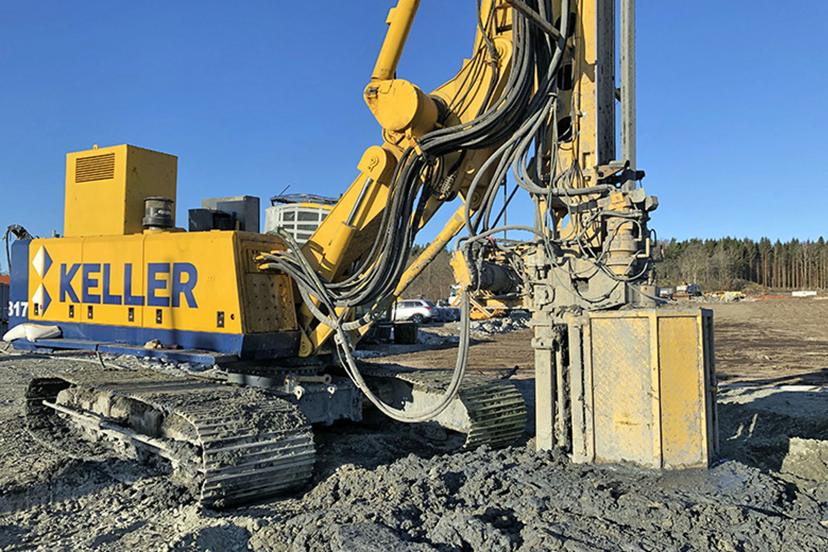 En stor og gul gravemaskin borrer ned i grunnen på et anleggsområde