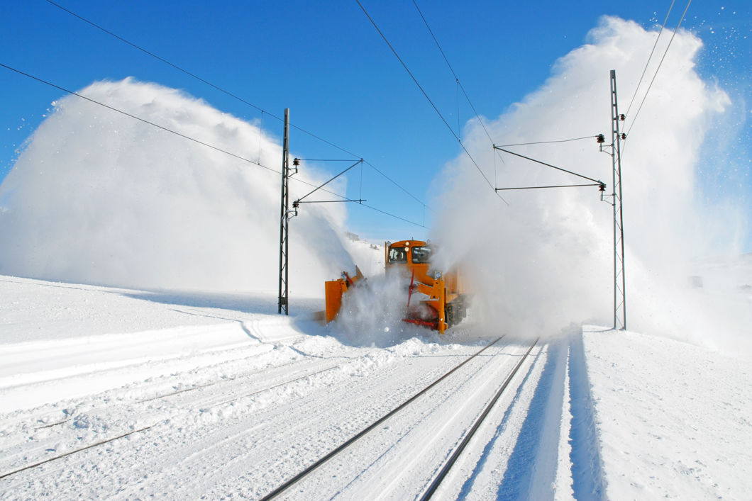 Snørydding på jernbanen hvor snøsprøyten står ut på begge sider av toget.