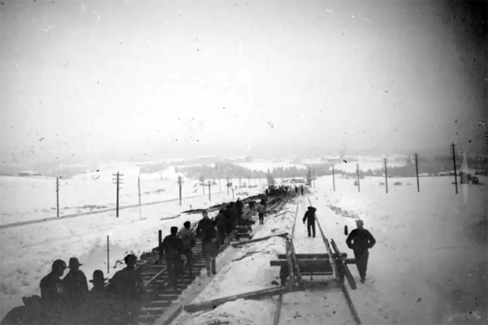 Mange i sving med manuell sporbygging, omgitt av snø og jorder.