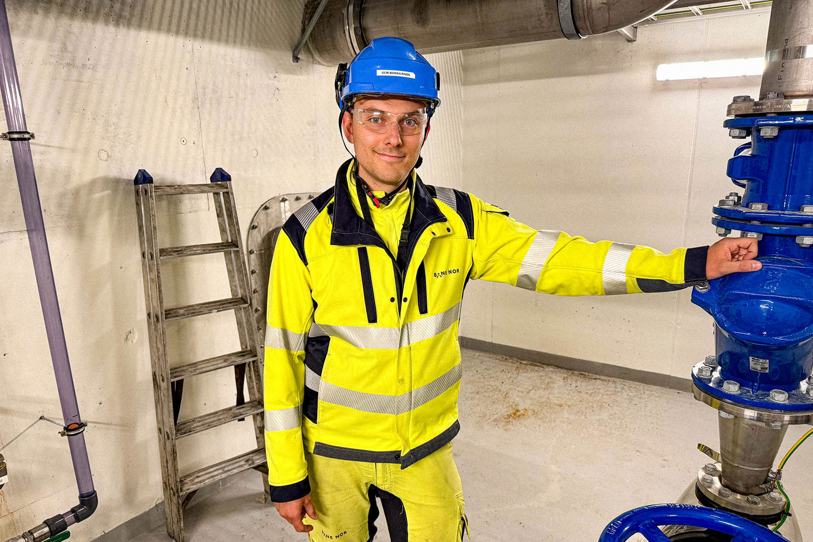 Mann i vernetøy lener seg mot pumpe.