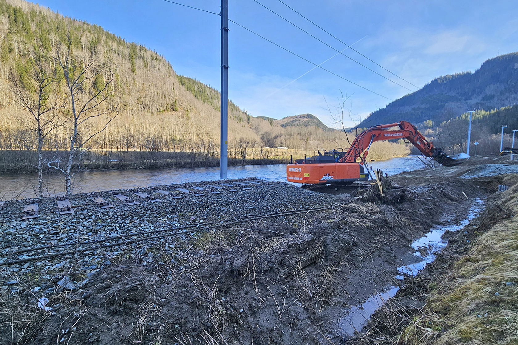 Gravemaskin i arbeid i jernbanesporet.