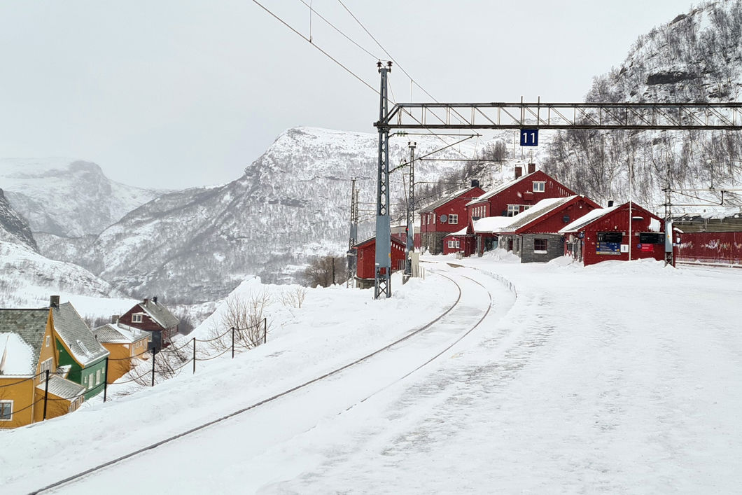 Bilde av Myrdal stasjon, med spor, bygninger og fjell i bakgrunnen.