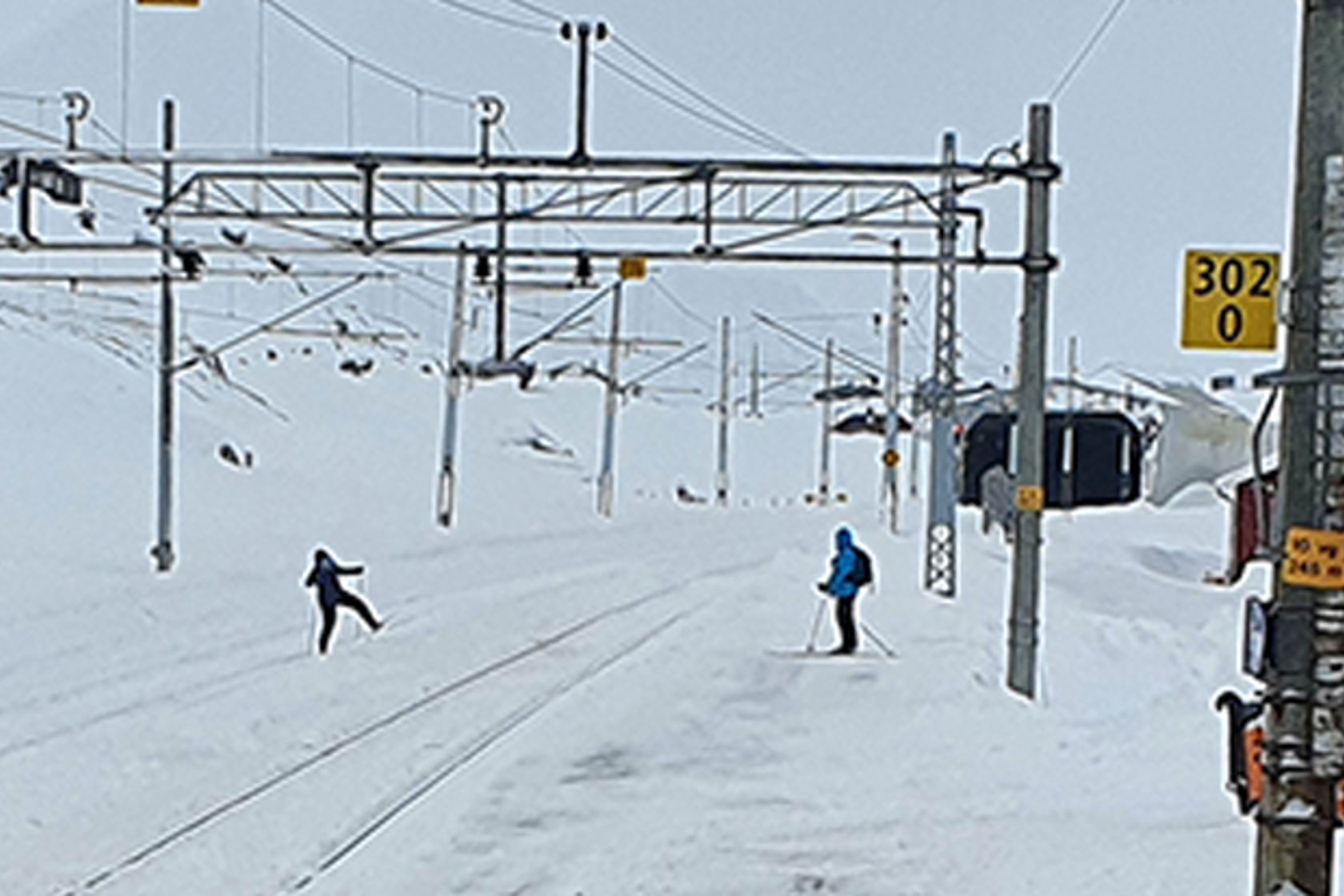 Bildet viser to skiløpere som går over jernbanesporet.