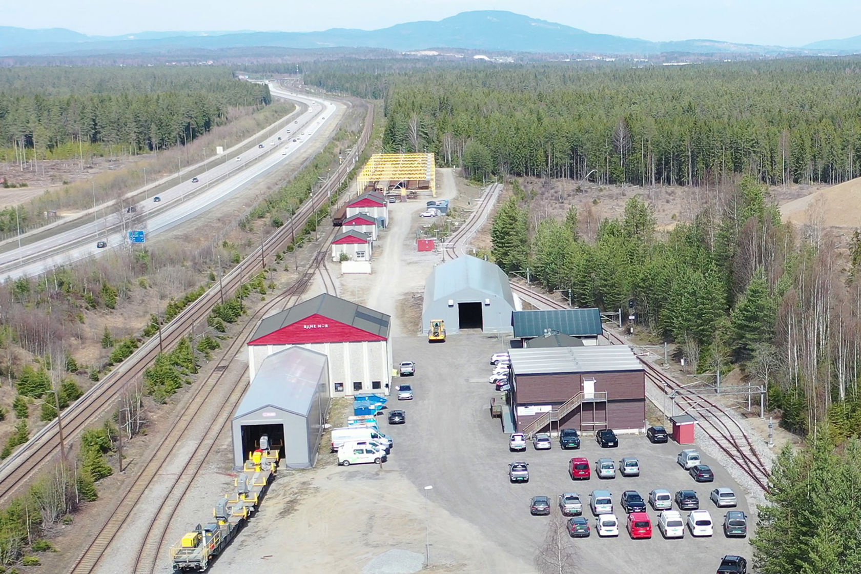 Dronefoto med skinnelageret i forgrunnen, Hovedbanen og E6. 