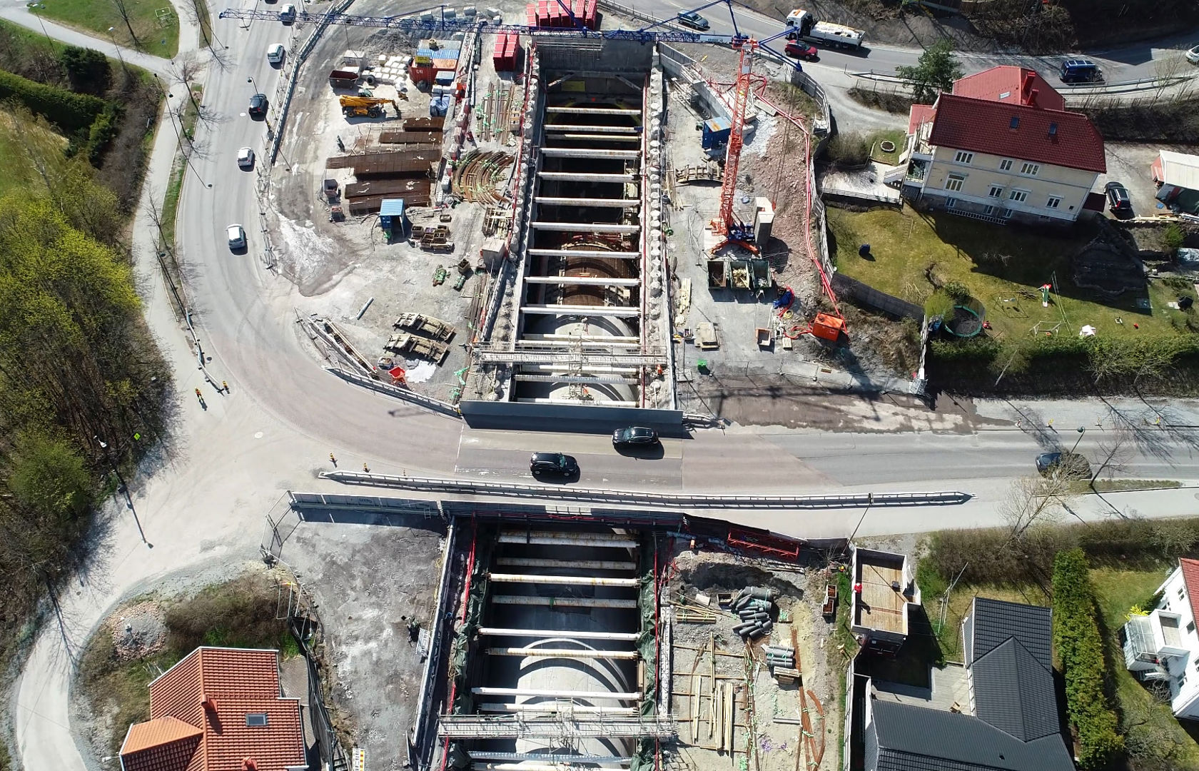 Anleggsområde med betongtunnel i kulvert. Biler kjører på bro over kulverten. Boligbebyggelse rundt.