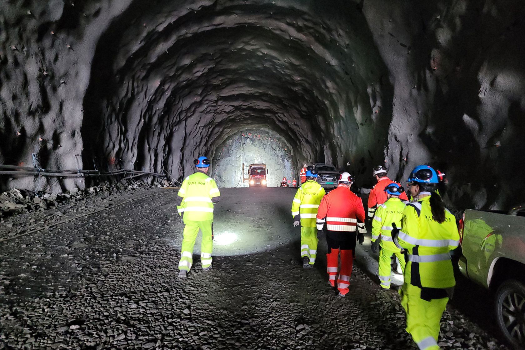 Bildet viser tunnelen fra innsiden og personer på befaring på vei inn.