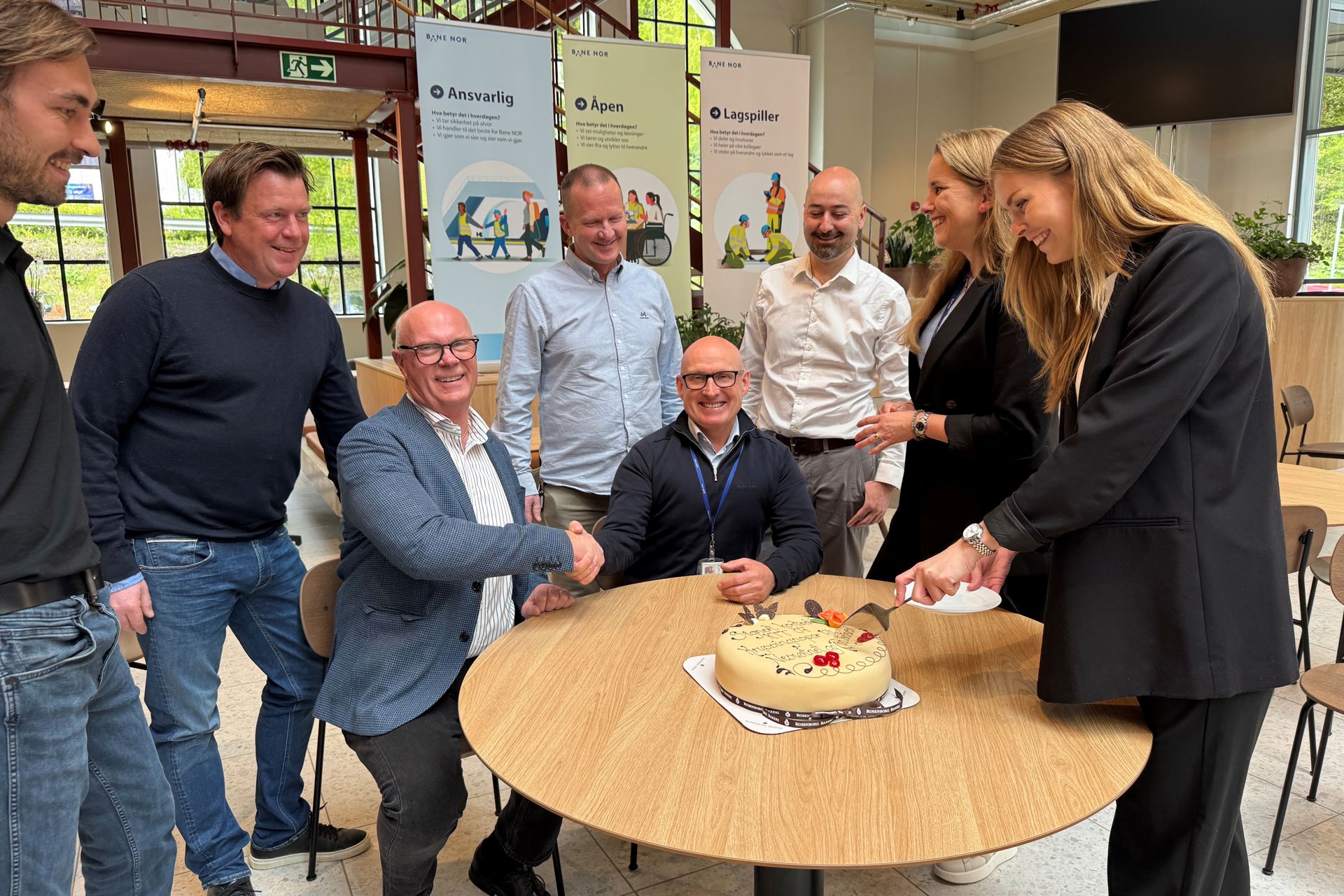 Skjærer kake for å feire signering av kontrakt