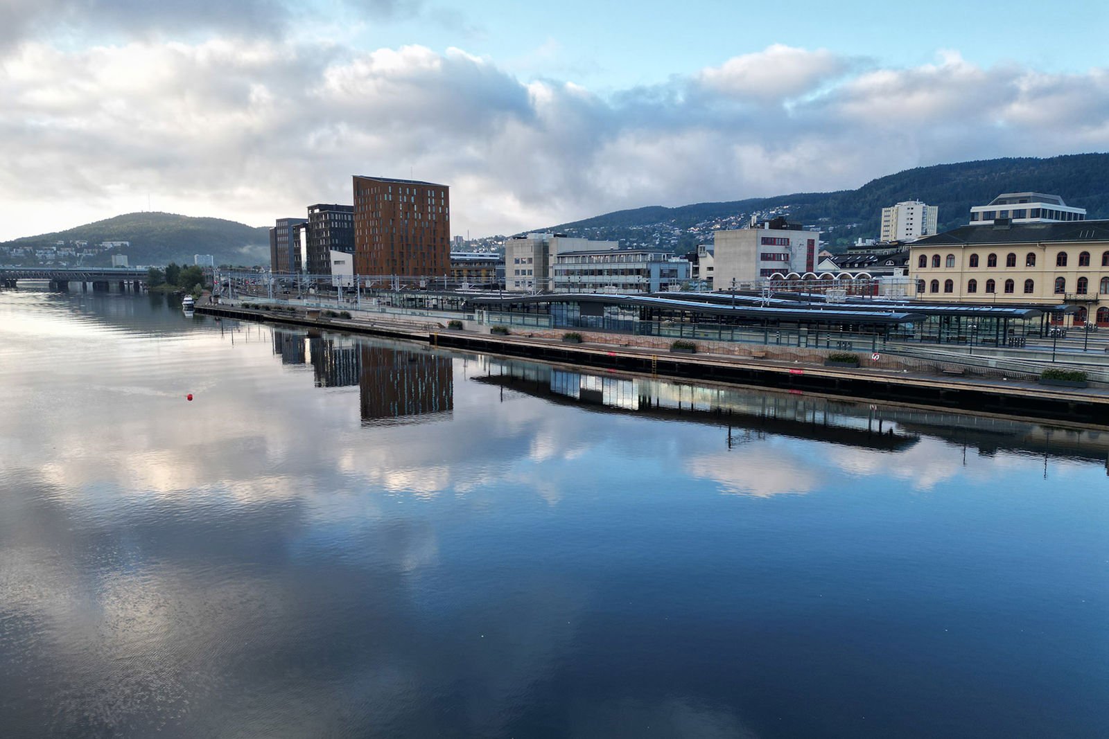 Dronefoto av stasjonen med Drammenselva i forgrunnen.
