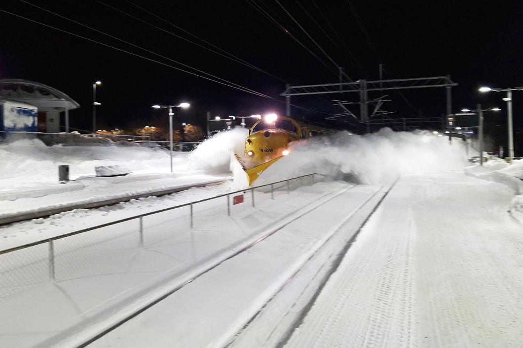 Et tog med plog brøyter seg gjennom snøen.