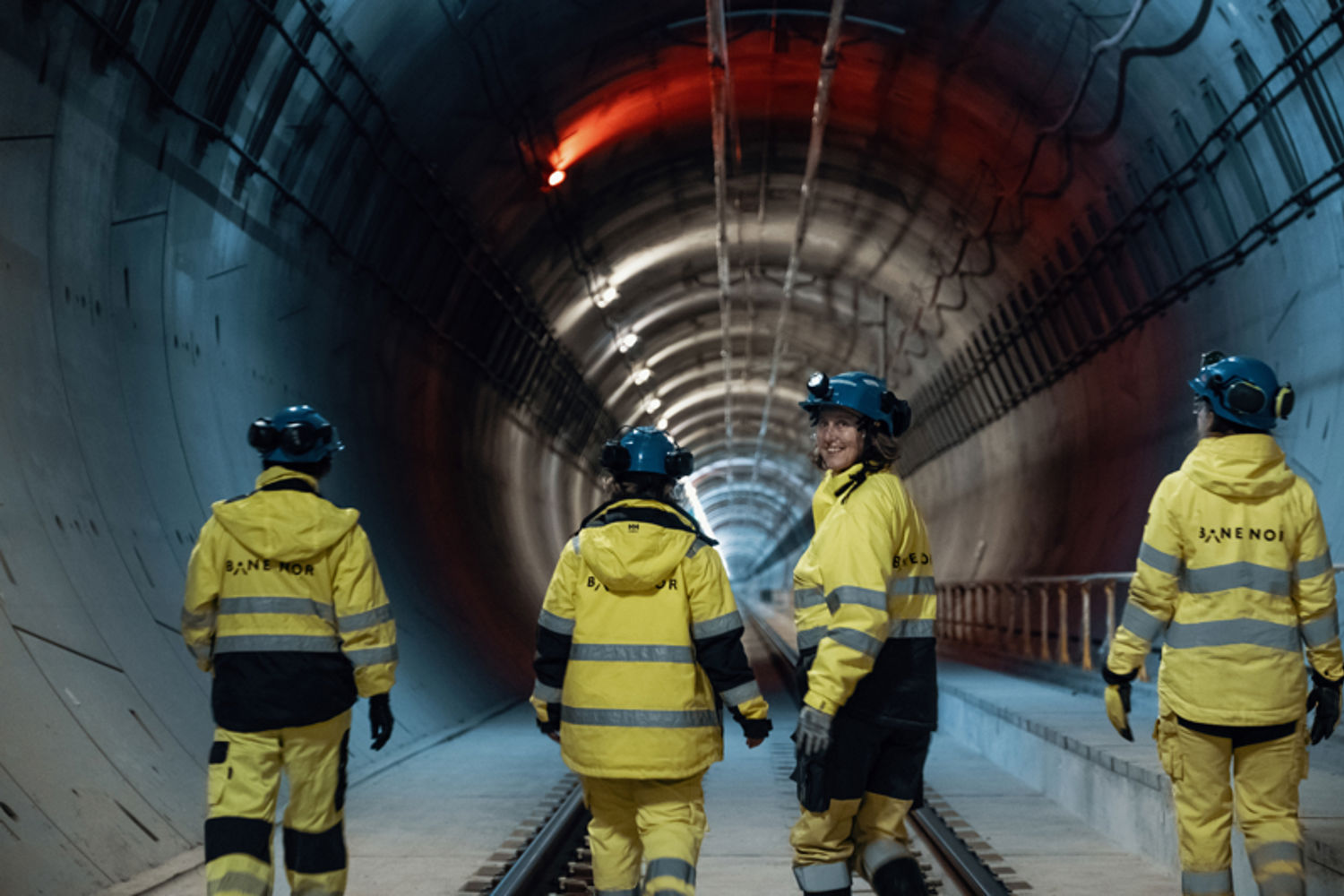 fire ansatte i gult vernetøy inne i en togtunnel.