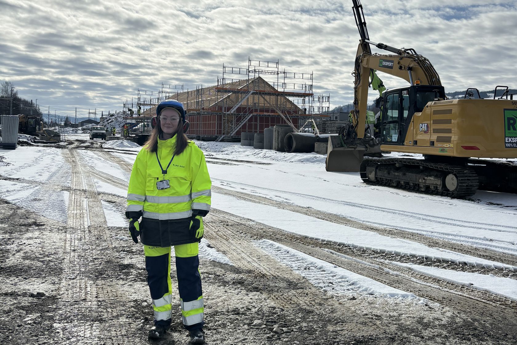 Sunniva står foran en kran ute på ett utbyggingsprosjekt.