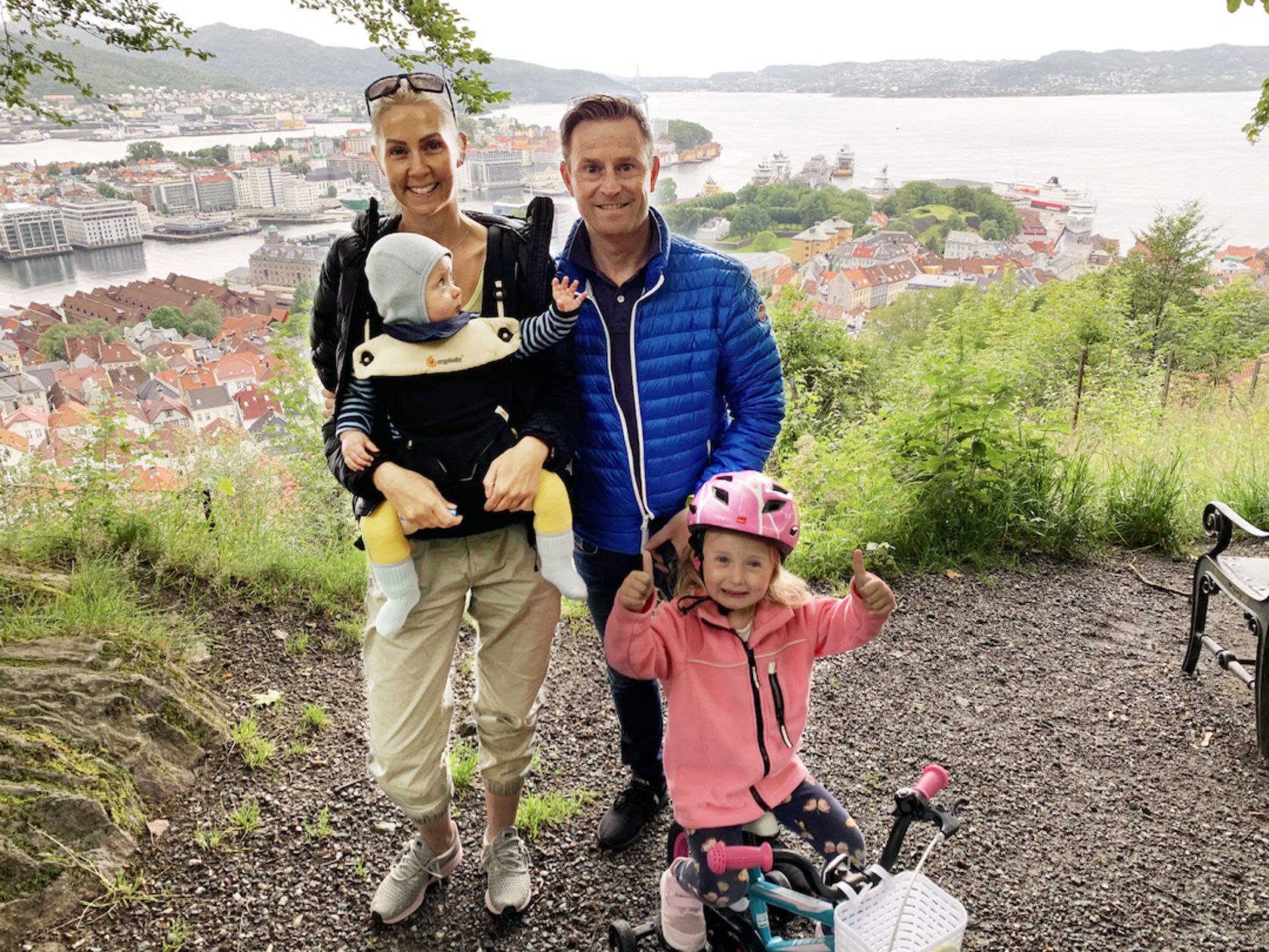 Mor, far og to barn med utsikt til sjøen i bakgrunnen
